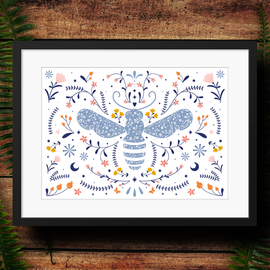 Framed artwork of a decorative bee design with flowers on a wooden surface