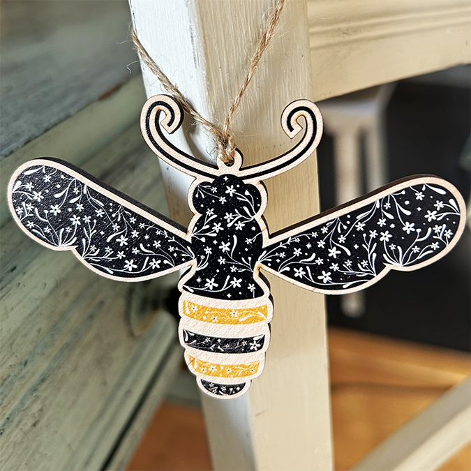 Folk art modern floral illustration of a bee on a wooden decoration