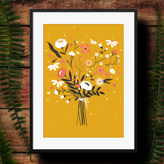 Framed artwork of a floral bouquet on a yellow background, leaning against a wooden surface with green leaves.