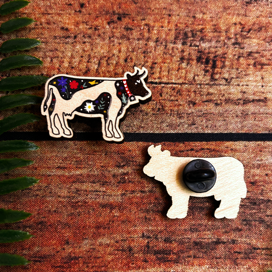 swiss cow wooden pin badge with alpine flora.