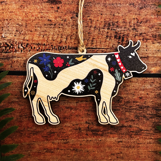 Decorative cow ornament with floral patterns on a wooden background