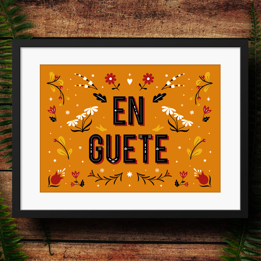 Framed artwork with 'EN GUETE' text and floral designs on a wooden background