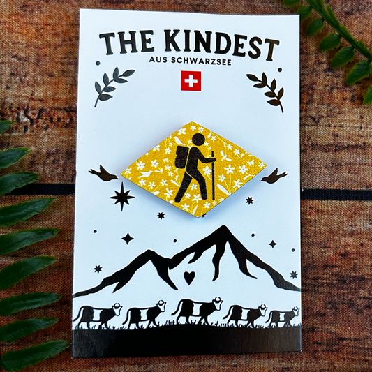 swiss hiking trail wanderweg symbol with flowers on a wooden pin badge shown on a backing card