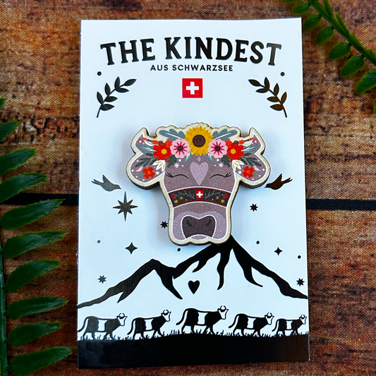 Swiss cow with flowers illustration on wooden pin badge, presented on backing card switzerland souvenir