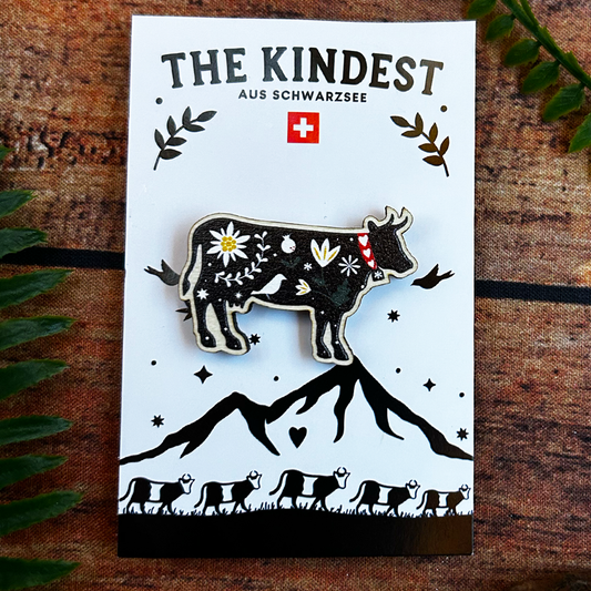 illustrated black cow with flowers on wooden pin badge. presented on backing card, switzerland souvenir