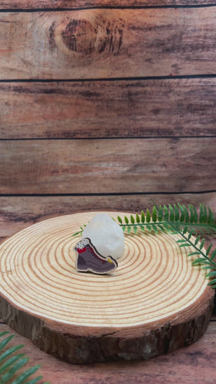 Video showing a wooden pin badge with illustrated hiking bot with edelweiss, swiss souvenir. 