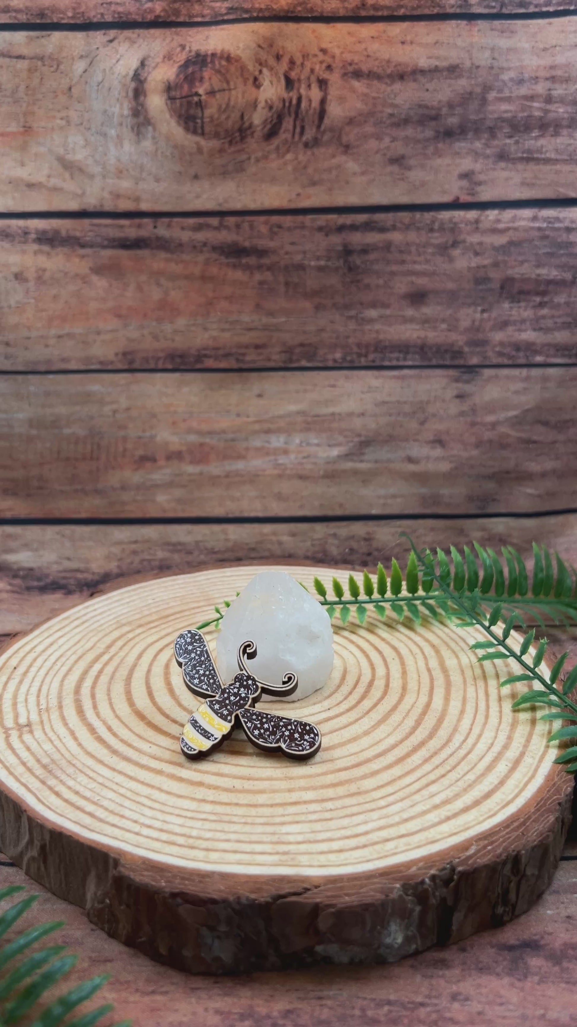 video showing floral illustration of a bee on a wooden pin badge